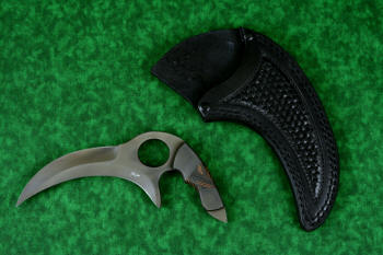 "Drepan" tactical karambit knife, obverse side view in T4 cryogenically treated 440C high chromium martensitic stainless steel blade, 304 stainles steel bolsters, orange/black G10 fiberglass epoxy composite laminate, sheath in leather shoulder, hand-tooled, nylon stitching, stainless steel reinforcement